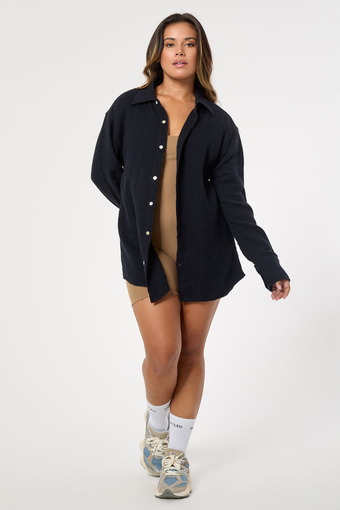 Oversized Ida black shirt with pearl buttons, long cuffs, and rounded hem. Made from breathable hemp and organic cotton.