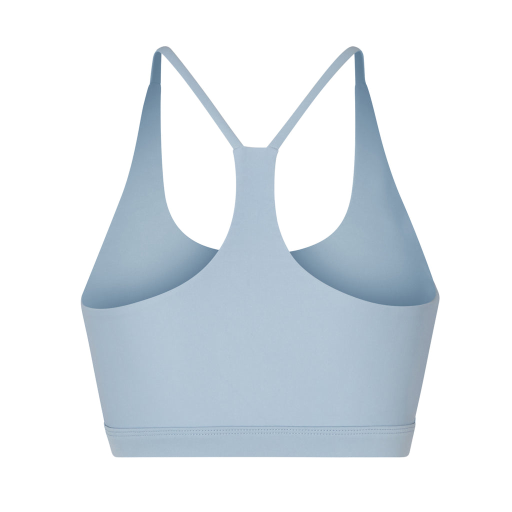 Classic racerback sports bra in light blue with seamless fit and removable padding. Perfect for light workouts and everyday wear, ghost image back view