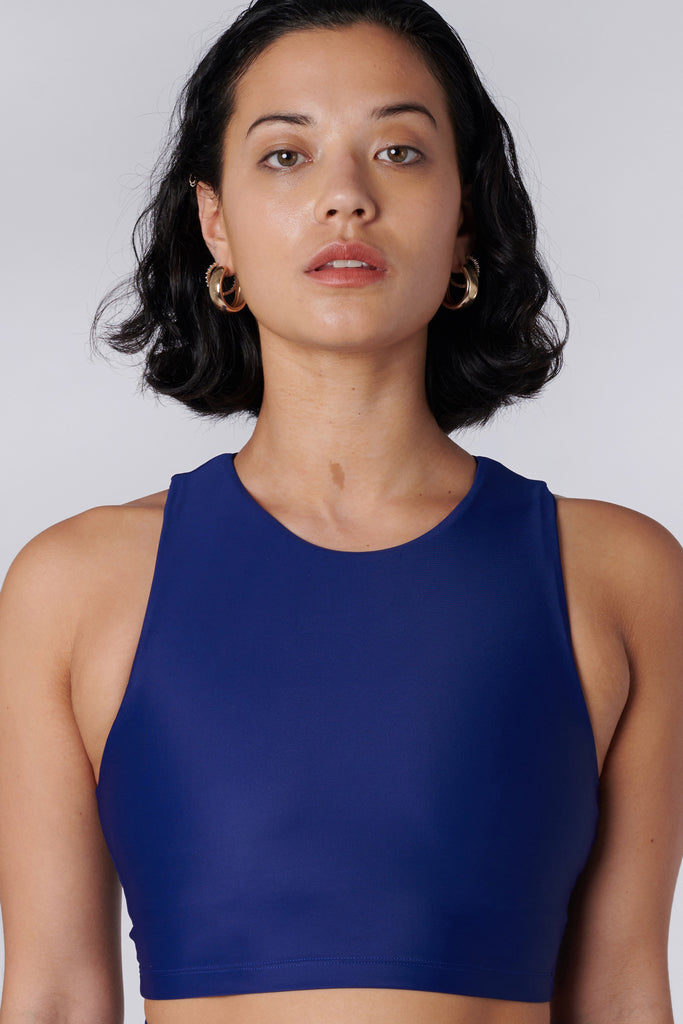 Award-winning navy blue crop top with a flattering cut, high neckline for coverage, and in-built sports bra. Medium impact support, perfect for day wear, close up