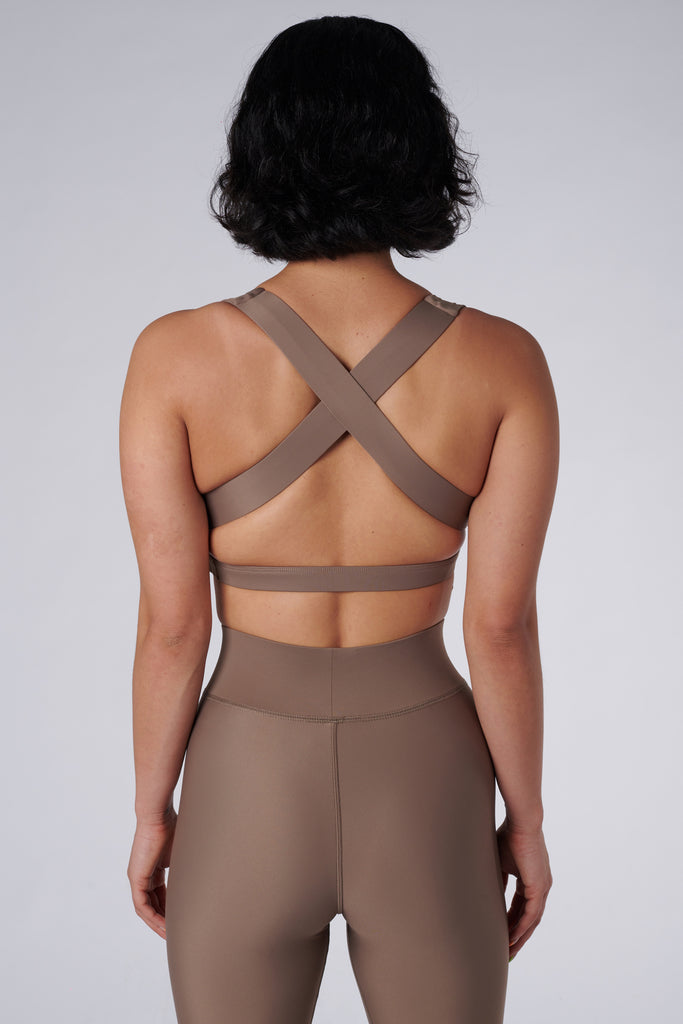 Beige, medium to high impact support with removable padding, strong elastic cross back straps, and adjustable gold-hook closure, back view