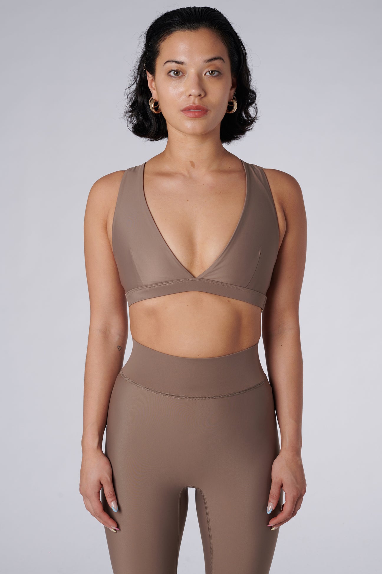 Beige, medium to high impact support with removable padding, strong elastic cross back straps, and adjustable gold-hook closure, front view