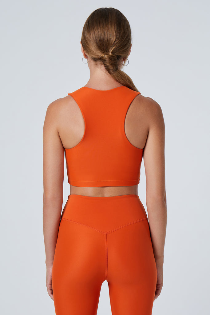 Award-winning orange crop top with a flattering cut, high neckline for coverage, and in-built sports bra. Medium impact support, perfect for day wear, back view