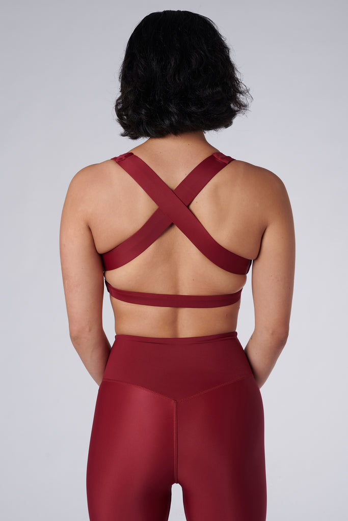 Dark red, medium to high impact support with removable padding, strong elastic cross back straps, and adjustable gold-hook closure, back view