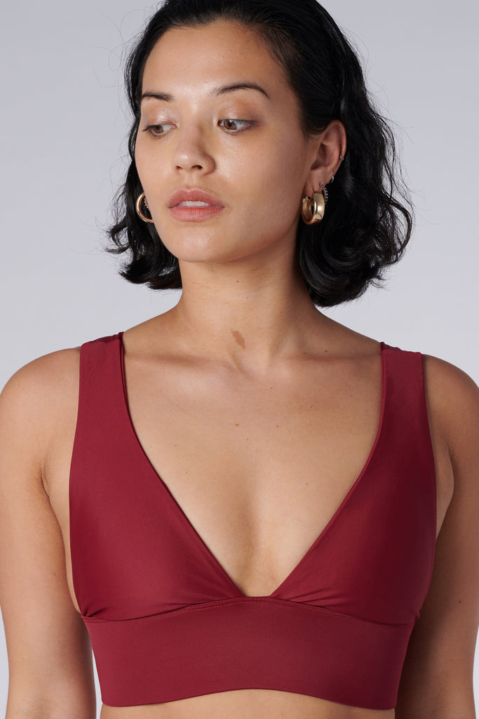 Classy and sexy sports bra in dark red with low-impact support, seamless fit, removable padding, and a wide under-bust elastic band close up